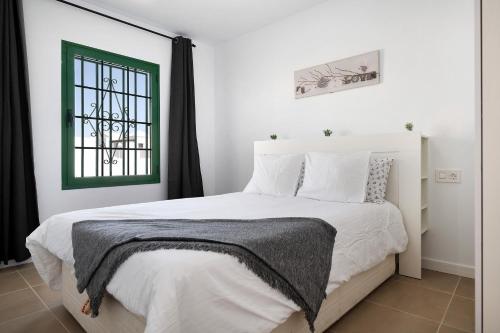 a bedroom with a large white bed with a window at Noaian in Puerto del Carmen