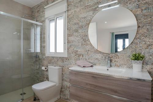 a bathroom with a toilet and a sink and a mirror at Villa Sandra solo familias in Cádiz