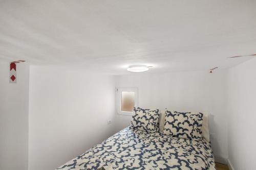 a bed in a room with a white wall at Loft Noemi - La Aldea in San Nicolás