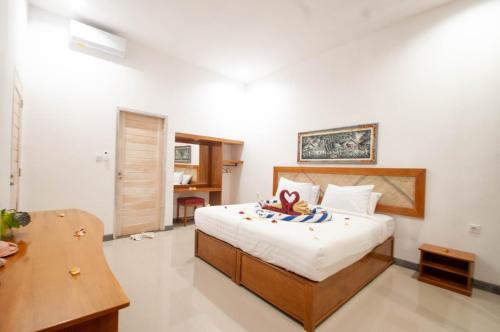 a bedroom with a bed and a desk and a table at Rumah Gajah by Kubukubali in Pemuteran