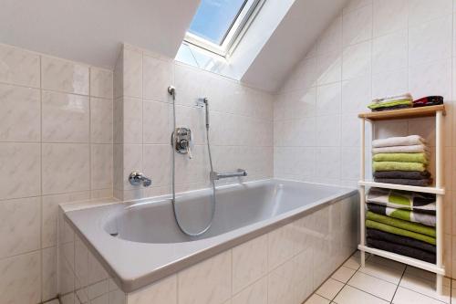 a white bathroom with a tub and a window at Ferienhaus am Mühlenbach, 110qm in Schwanau