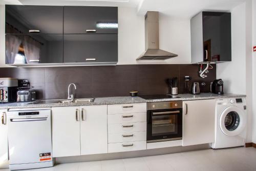 a kitchen with white cabinets and a washer and dryer at Apartment Beach Waves Home in Nazaré