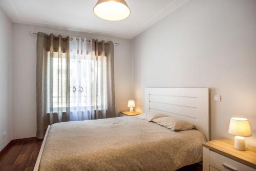 a bedroom with a bed and two lamps and a window at Apartment Beach Waves Home in Nazaré