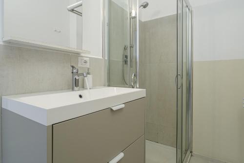 a white bathroom with a sink and a shower at Cormorani - Appartamento 13 in Golfo Aranci