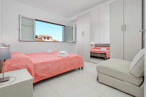 a bedroom with a bed and a chair and a mirror at Cormorani - Appartamento 13 in Golfo Aranci