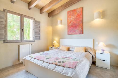 a bedroom with a large bed and two windows at Casa Cascada in Costitx