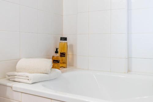 a white tiled bathroom with a tub and towels at 180-degrees sea view with pool in Benitachell