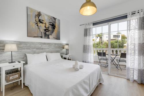 a white bedroom with a large bed and a window at La Villa in Tarajalejo