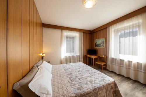 a bedroom with a bed and a desk in it at Appartamento Primavera 1 in Moena