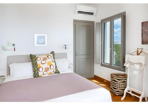 a white bedroom with a bed and a window at Luna Rossa Milos - Olive Home in Provatas