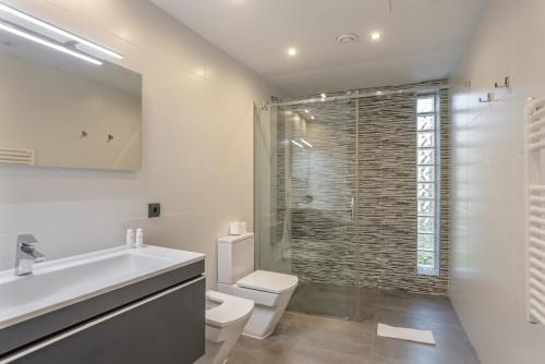 a bathroom with a toilet and a sink and a shower at Villa Elite Maribiza in Cala Llena
