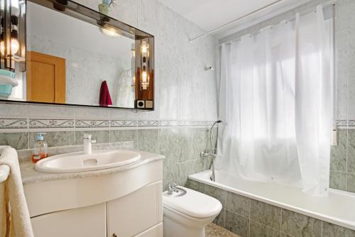 a bathroom with a sink and a toilet and a mirror at Playa de Chilches in Chilches