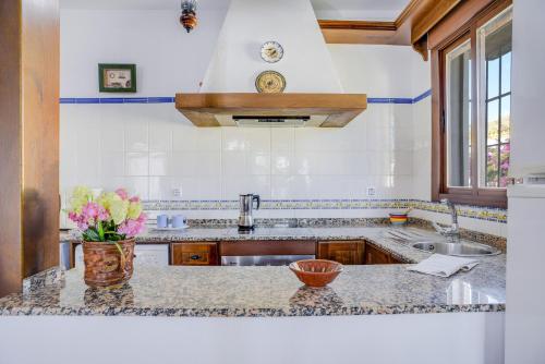 a kitchen with a sink and a vase of flowers on a counter at Casa Villanueva 2 - Sólo Familias in Conil de la Frontera