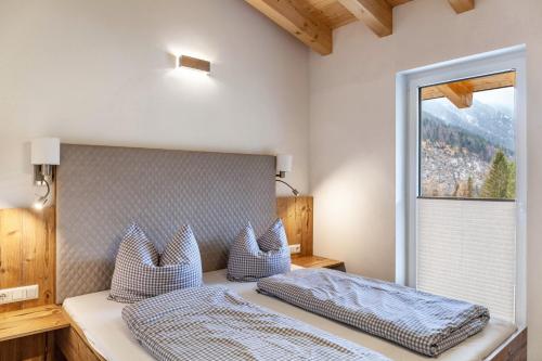 a bedroom with a bed with pillows and a window at Ferienwohnung Daniel in Ehrwald