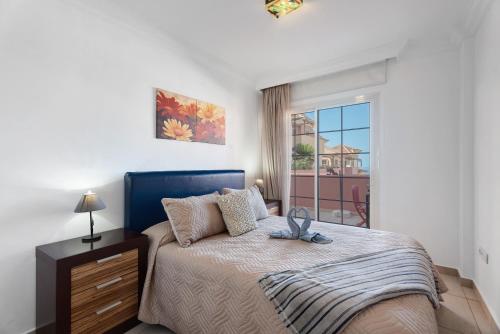 a bedroom with a bed with a blue headboard and a window at terrazas del duque fase2 in Adeje