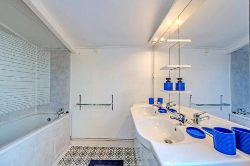 a white bathroom with a sink and a tub at Ty Abéric maison en front de mer in Ploudalmézeau