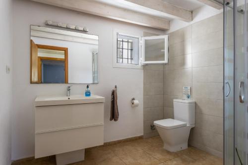 a bathroom with a toilet and a sink and a mirror at Finca Can Paci in Santa Eularia des Riu