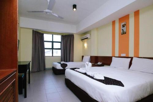 a hotel room with two beds and a desk at Sun Inns Setiawan in Sitiawan