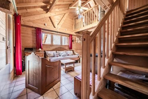 a living room with a staircase in a log cabin at Chalet 6p Confort - Le Morlay in Verchaix
