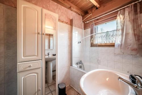a bathroom with a tub and a sink and a window at Chalet 6p Confort - Le Morlay in Verchaix