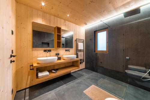 two sinks in a bathroom with wooden walls at Ratscheinerhof App Waldruhe in Lazfons