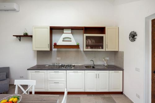 a kitchen with white cabinets and a sink at Villa Degli Dei in Agerola