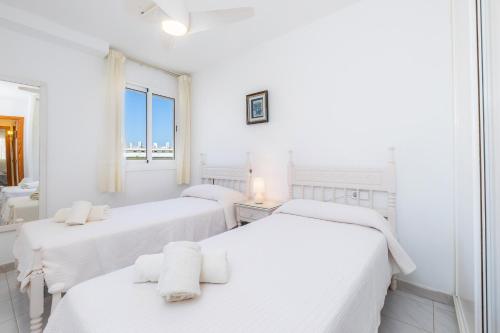 two beds in a white room with a window at Apartment La Veleta with Sea View in El Port