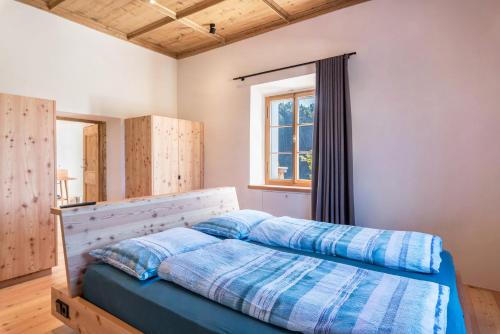 a bedroom with a bed with blue sheets and a window at Hof im Thal Apt Zirbe in Aldino