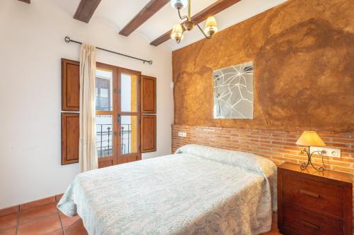 a bedroom with a bed and a brick wall at Cueva Del Gollisno in Chulilla