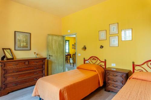 a yellow bedroom with two beds and a dresser at Tramonto al Rifugio Arcobaleno in Popiglio