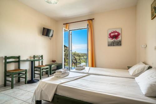 a hotel room with two beds and a balcony at Anemona studio D in Kefallonia