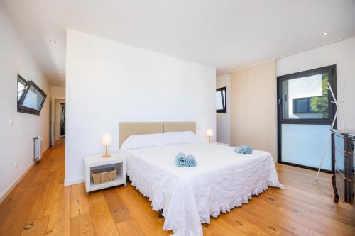 a bedroom with a white bed and a television at Es Nautic in Porto Cristo