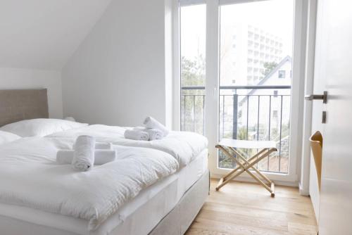 a white bedroom with a bed and a balcony at Strandroggen in Böhl