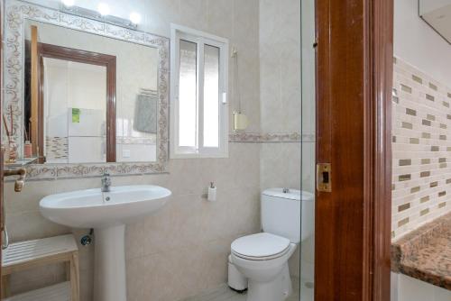 a bathroom with a toilet and a sink and a mirror at Piso Río de Conil in Conil de la Frontera