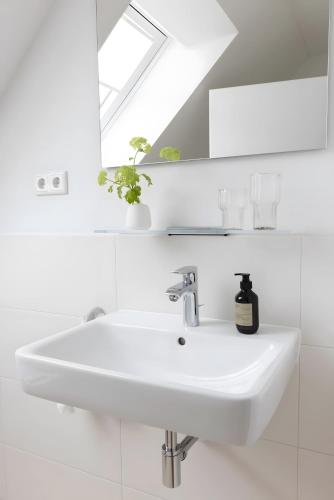 a white bathroom with a sink and a mirror at Strandroggen in Böhl