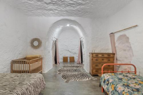 a bedroom with two beds and a dresser in a room at Casa Cueva Rural, Calima in Juncalillo