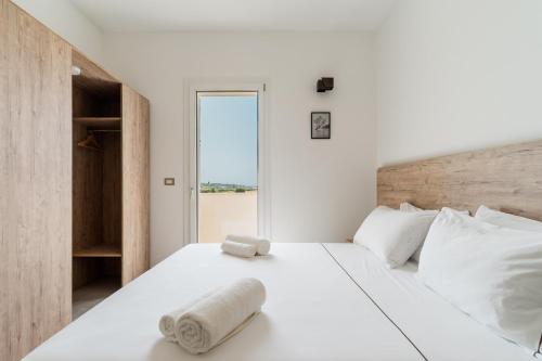 a bedroom with a large white bed with a window at Le scuderie 10 in Galatone