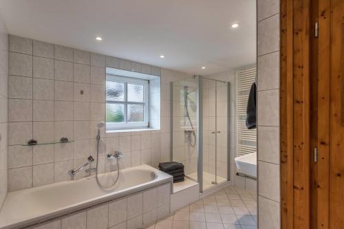 a bathroom with a tub and a shower and a sink at Zuhaus am See in Gstadt am Chiemsee