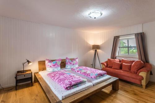 a bedroom with a bed and a red couch at Zuhaus am See in Gstadt am Chiemsee