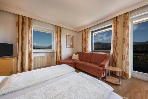 a hotel room with two beds and a couch and windows at Residence Kronstein - Fewo 3 in Tesimo