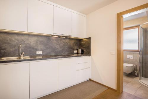 a white kitchen with a sink and a toilet at Rosalpina Apt 1 in San Vigilio Di Marebbe