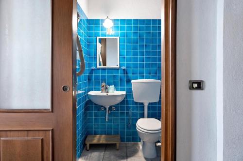 a blue tiled bathroom with a toilet and a sink at Casa Vacanze il Ginepro in Sinio