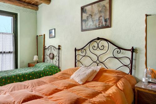 a bedroom with a large bed with an orange blanket at Casa Vacanze il Ginepro in Sinio