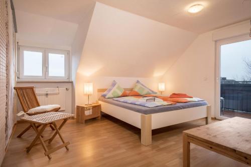 a bedroom with a bed and a chair and a window at Ferienwohnung Tasoli in Lindau