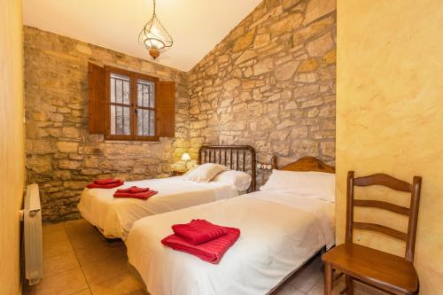 two beds in a room with a stone wall at Ca La Pascola in Guimerá