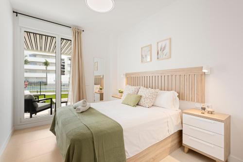 a white bedroom with a bed and a balcony at Horus Beach Paradise in Torre del Mar