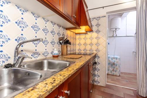 a kitchen with a stainless steel sink and blue and white tiles at Casa de Ses Roques in Ciutadella