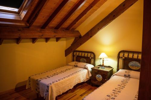 a bedroom with two beds and a wooden ceiling at Kabila Enea 2 in Uztárroz
