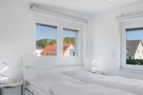 a white bedroom with a bed and two windows at Luxusvilla Neubau 1 in Oberasbach