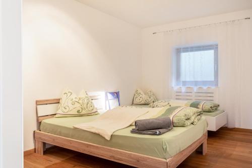 two beds in a room with white walls and a window at Apartement Santner in Siusi